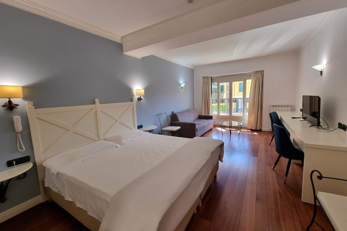 Habitación de hotel con una cama grande, un escritorio, una silla y una mesita.