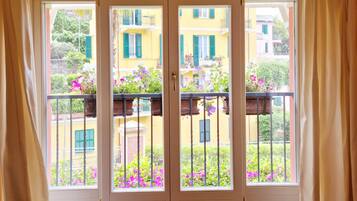 A room with a large sliding glass door leading to a balcony with a view of neighboring buildings and balconies.