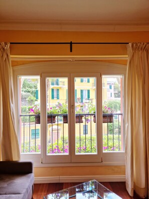 Une pièce dotée d’une grande porte-fenêtre coulissante donnant sur un balcon d’où l’on peut admirer les bâtiments et les balcons des environs.