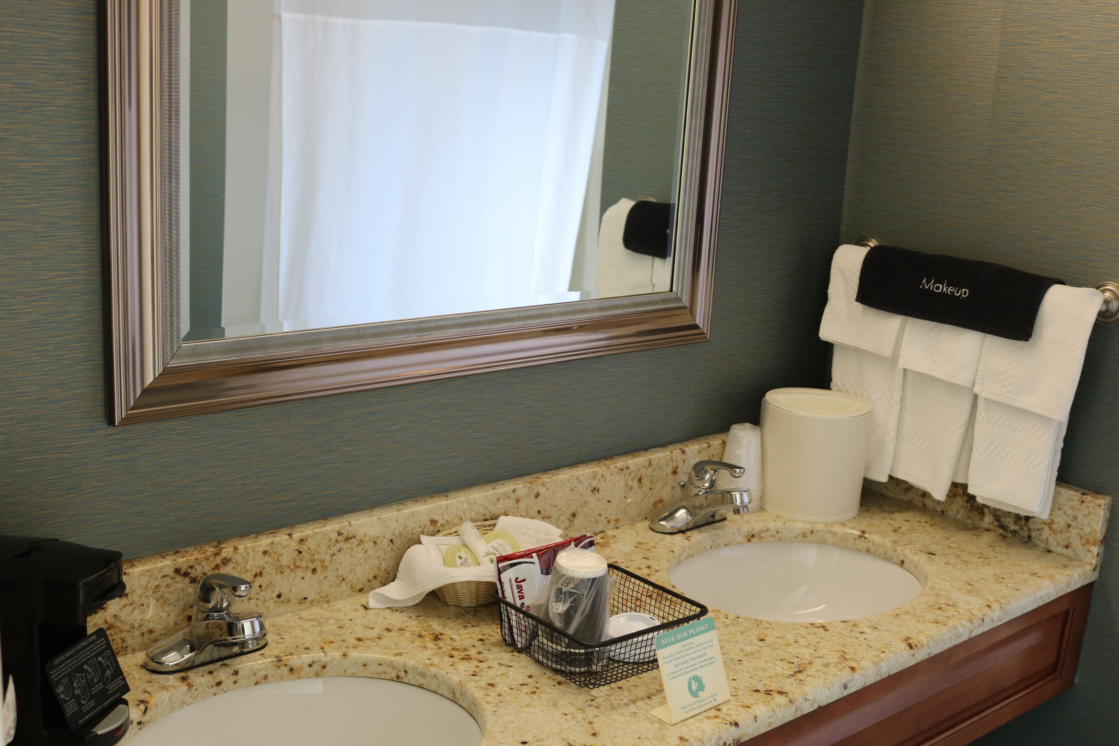 A bathroom with two sinks, a mirror, and a towel rack with a 'Makeup' towel.