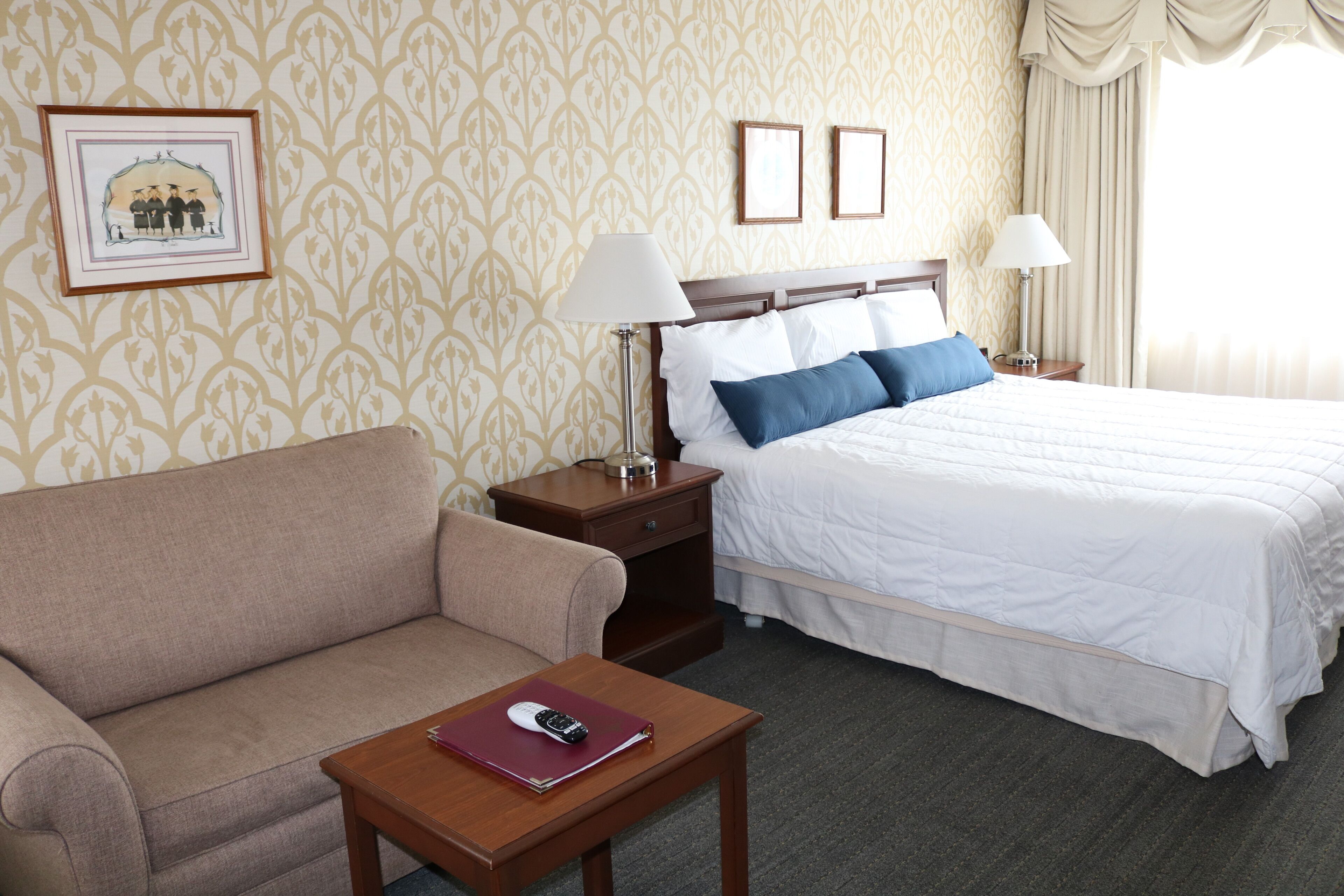 Quarto de hotel com cama, sofá, mesa de cabeceira e uma mesa.
