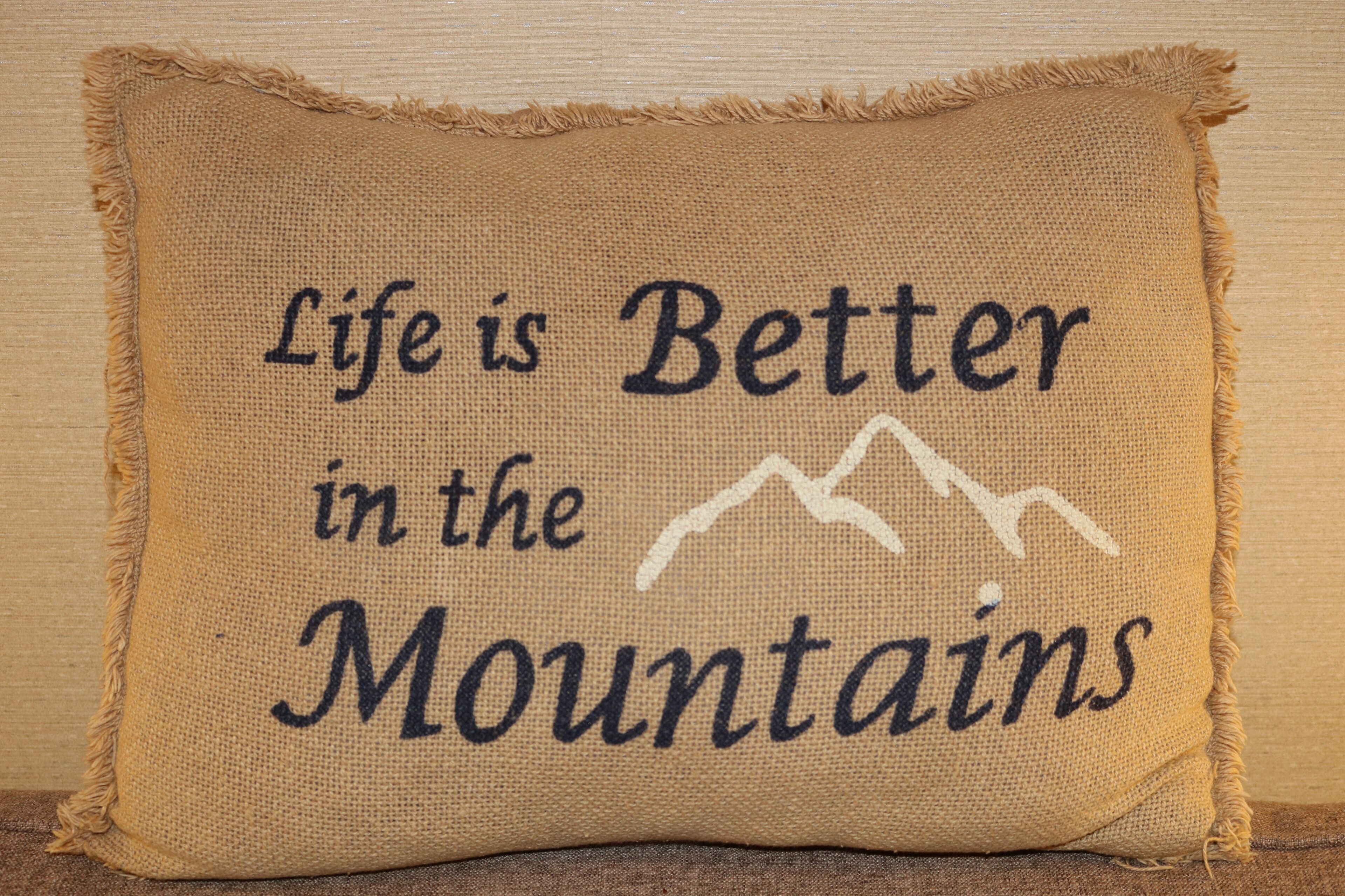 A pillow with the text "Life is Better in the Mountains" and a mountain illustration.