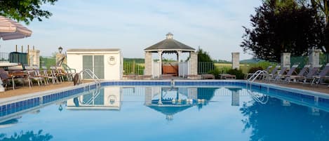 Una piscina con sillas de descanso y un pabellón.