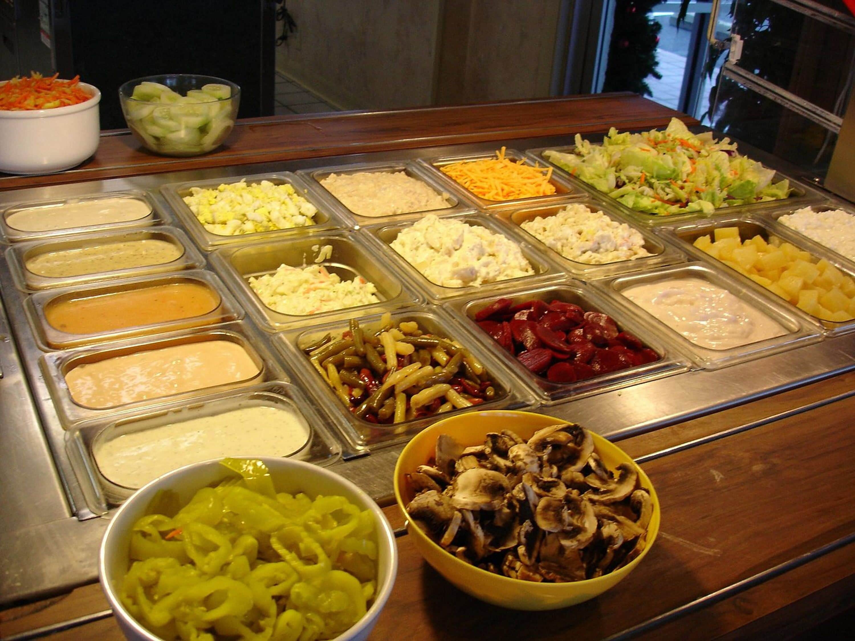 A buffet with various food items including salads, coleslaw, and different types of dips.