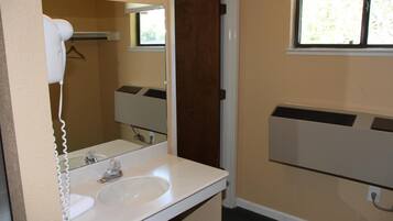 A bathroom with a white sink, a mirror, a towel rack, and a window.