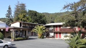 A motel with a parking lot, a flag, and a building with a red door.