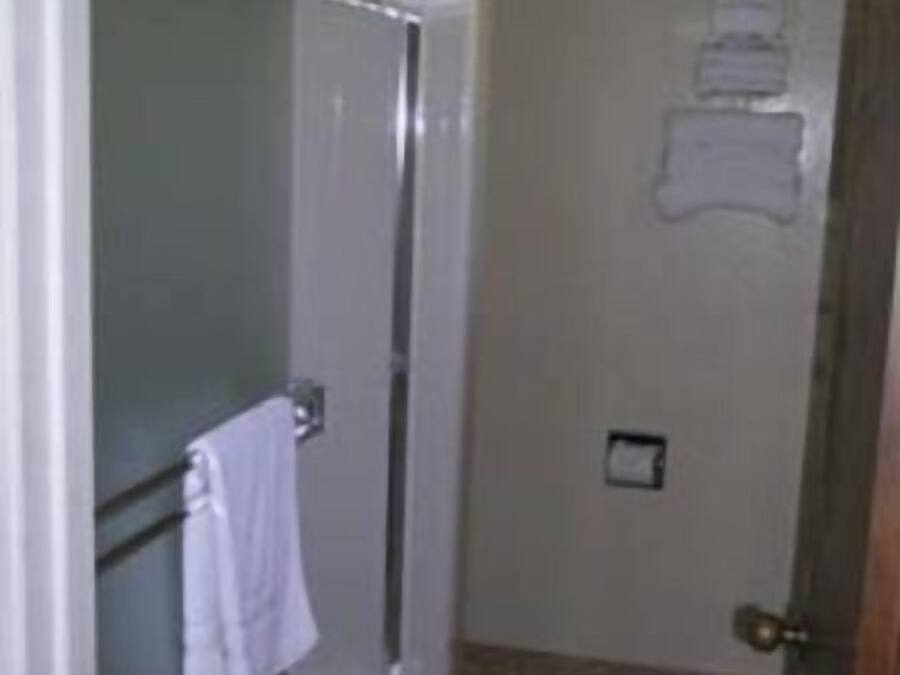 A bathroom with a glass shower enclosure, a towel rack, and a wall-mounted towel dispenser.
