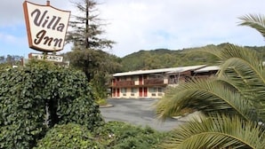 A Villa Inn motel with a signboard, surrounded by greenery and a mountainous backdrop.