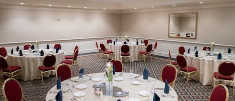 A conference room with round tables, red chairs, and a carpeted floor.