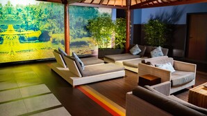 A modern lounge area with sofas and a large mural of a tropical landscape.