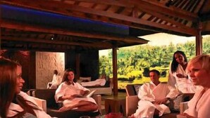 A group of people seated at a table in a covered outdoor area with a view of a forested landscape.