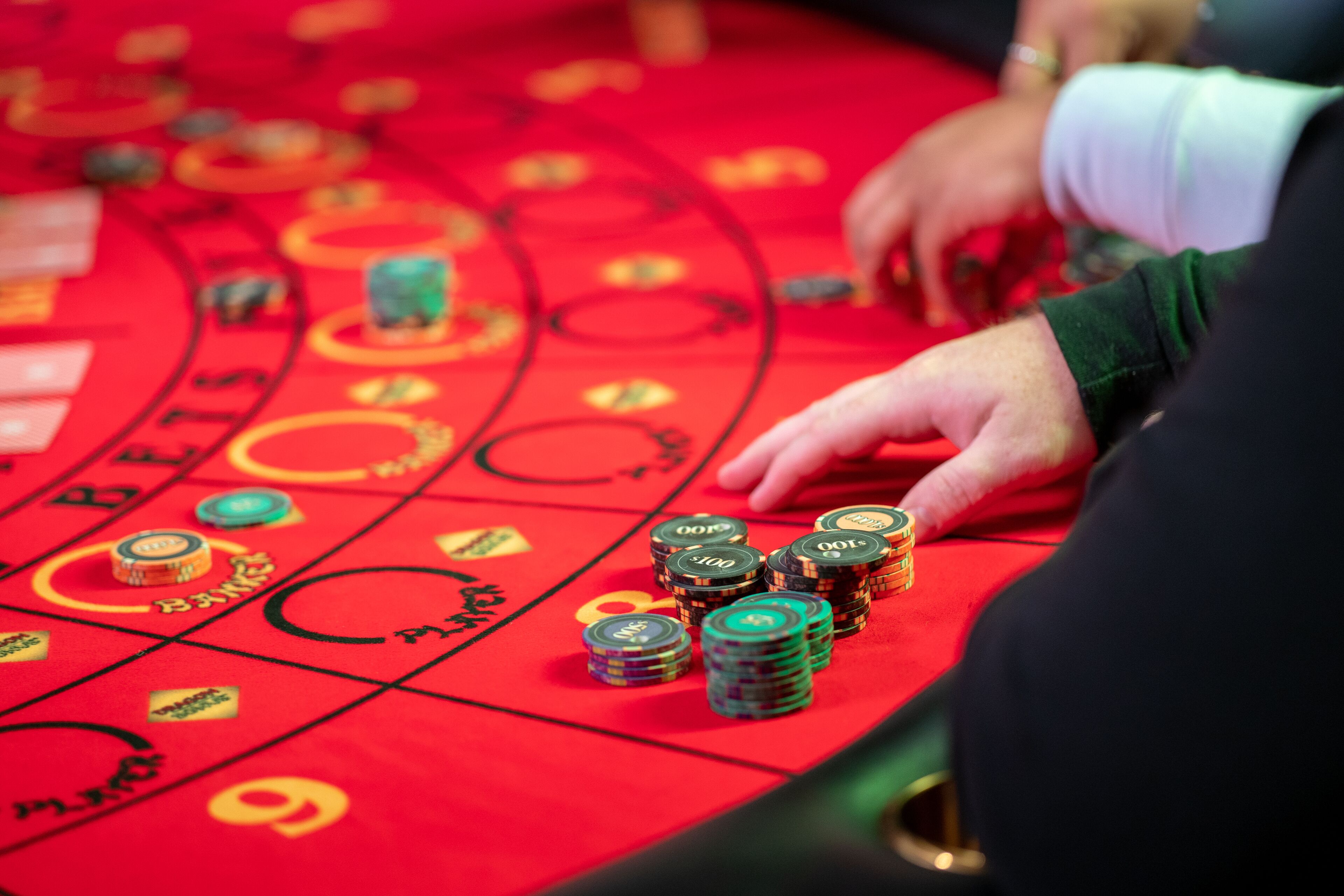 A casino table with stacks of chips and a red felt surface with betting area markings.
