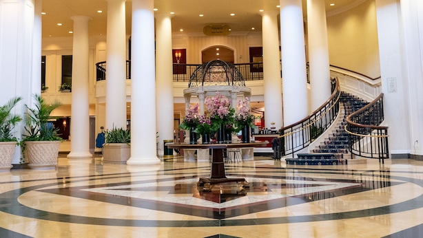 A spacious lobby with a central fountain, a grand chandelier, and a curved staircase.