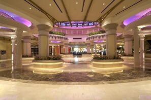 Een ruime lobby met een centrale fontein, marmeren vloeren en zuilen met beplanting.