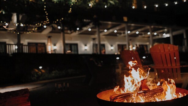 A fire pit with flames, surrounded by outdoor seating and string lights. - Kimpton Taconic Hotel by IHG (Manchester)