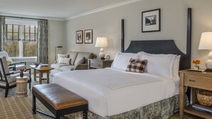 A hotel room with a large bed, a sofa, a chair, a nightstand with a lamp, and a window with curtains. - Kimpton Taconic Hotel by IHG (Manchester)