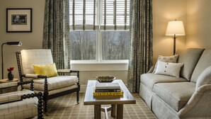 A living room with a sofa, armchair, and a table with books.