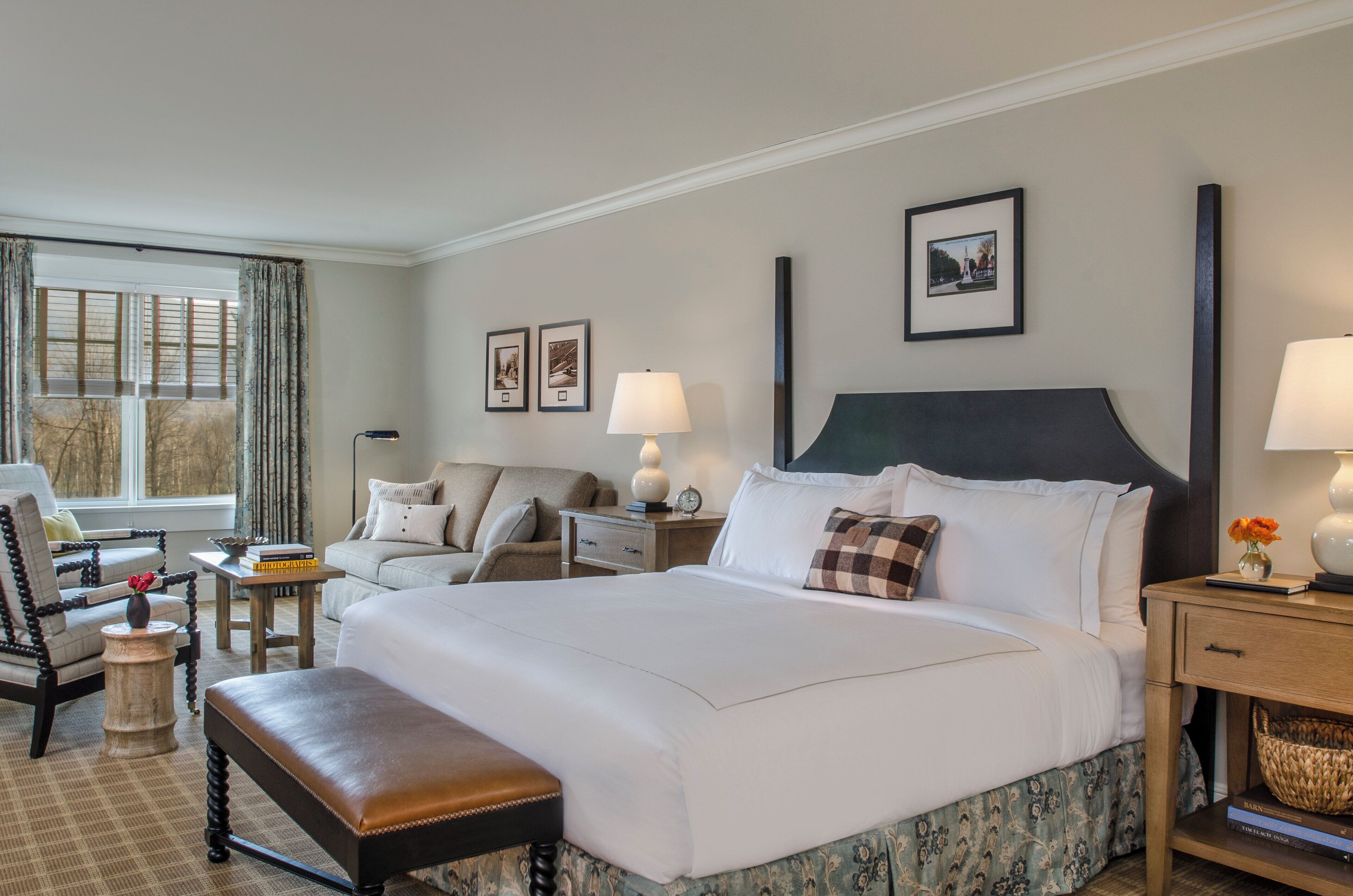 A hotel room with a large bed, a chair, a desk, and a lamp.