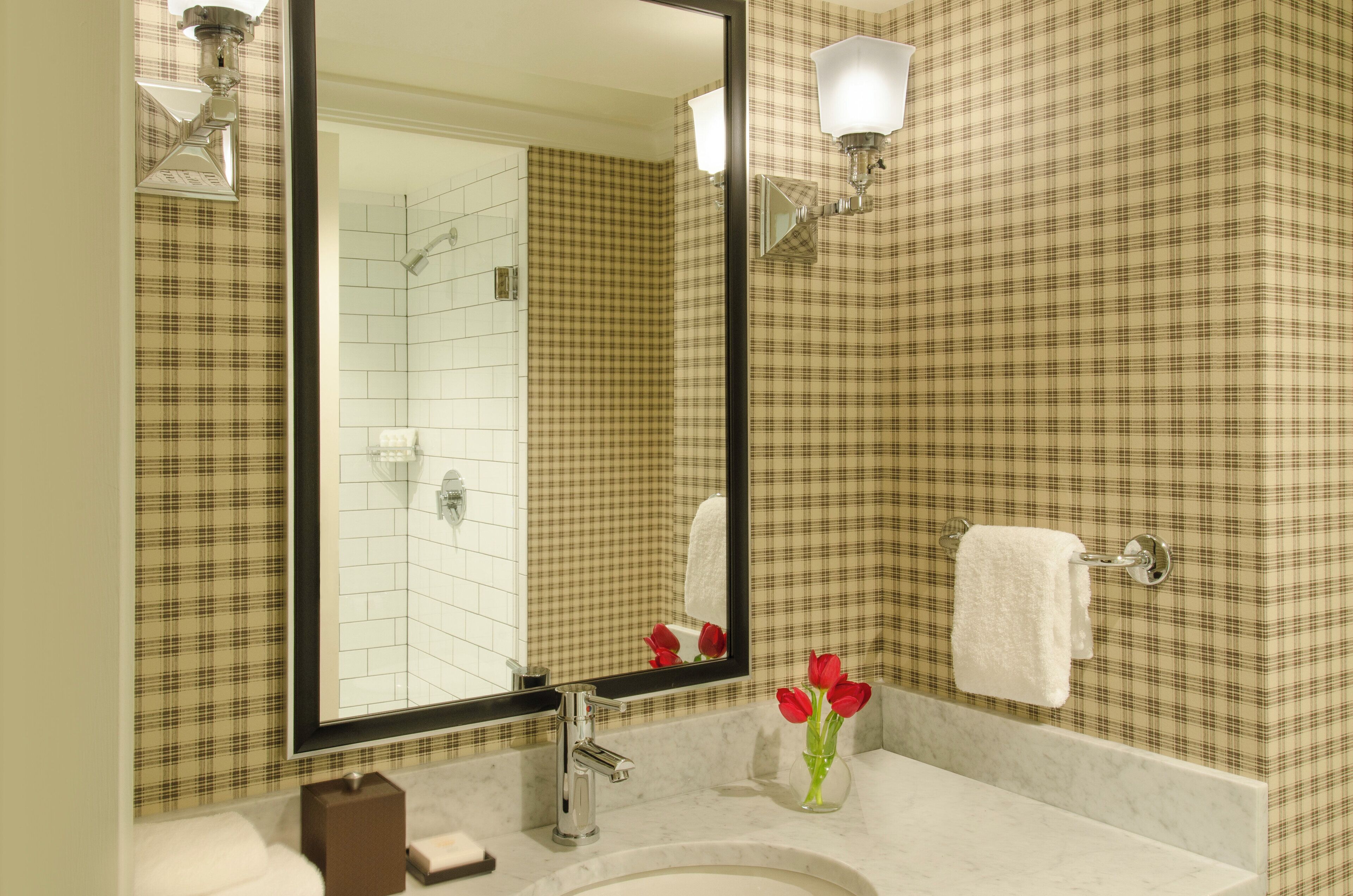 A bathroom with a large mirror, a sink, a towel rack, and a wall with a checkered pattern.