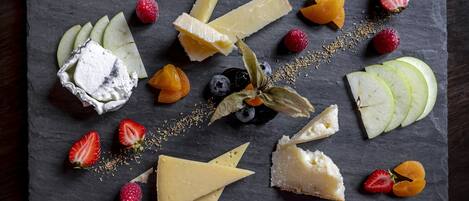 Eine Auswahl an Käse und Früchten auf einer Schieferplatte.