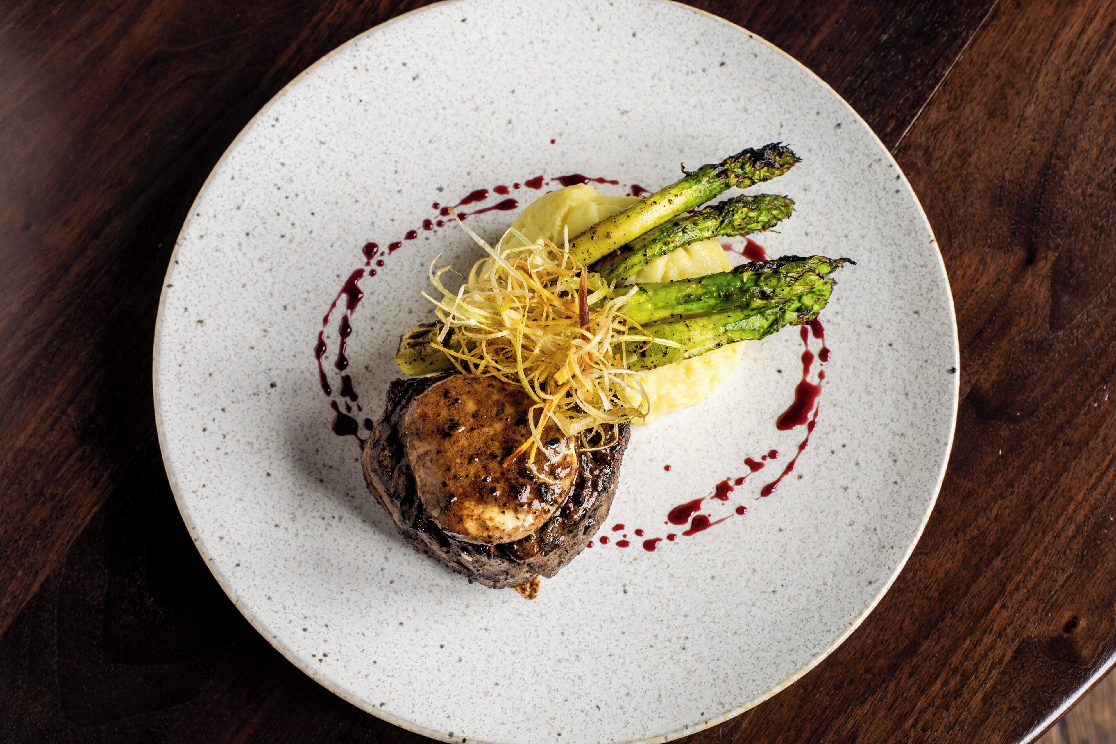 A plate with a steak, asparagus, and mashed potatoes.