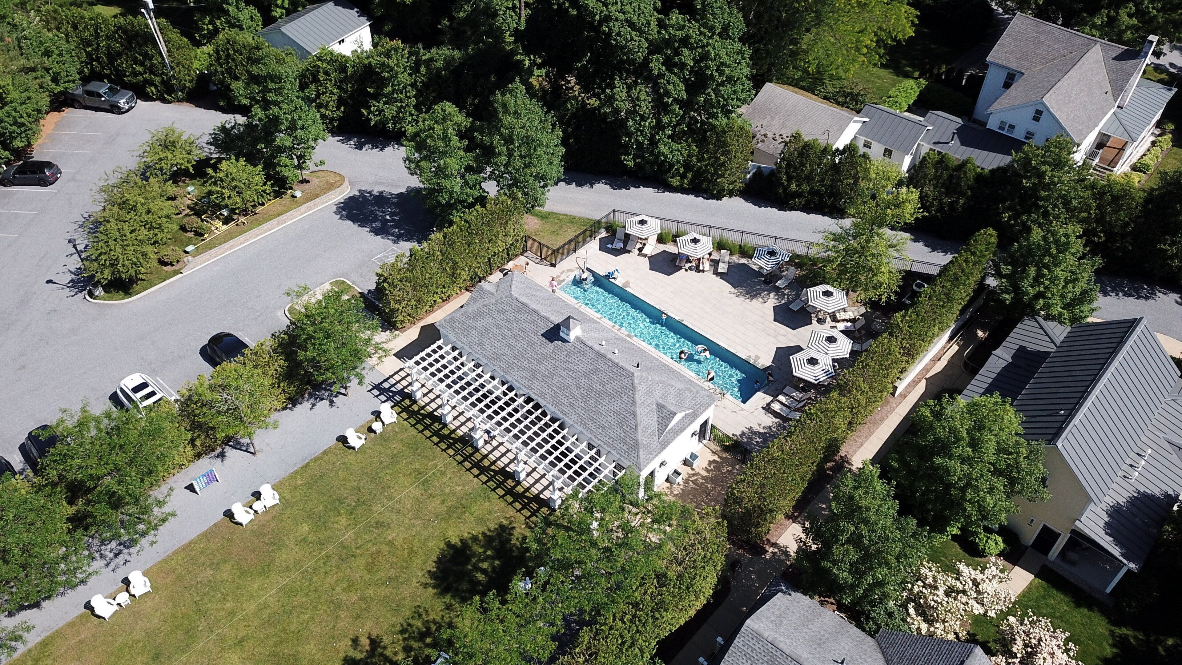 An aerial view of a residential area with a swimming pool, lounge chairs, and a covered patio area.