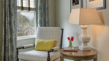 A room with a chair, a lamp, and a window with curtains.