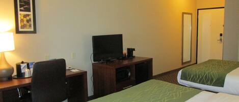 Una habitación de hotel con escritorio, televisión, cama y puerta.