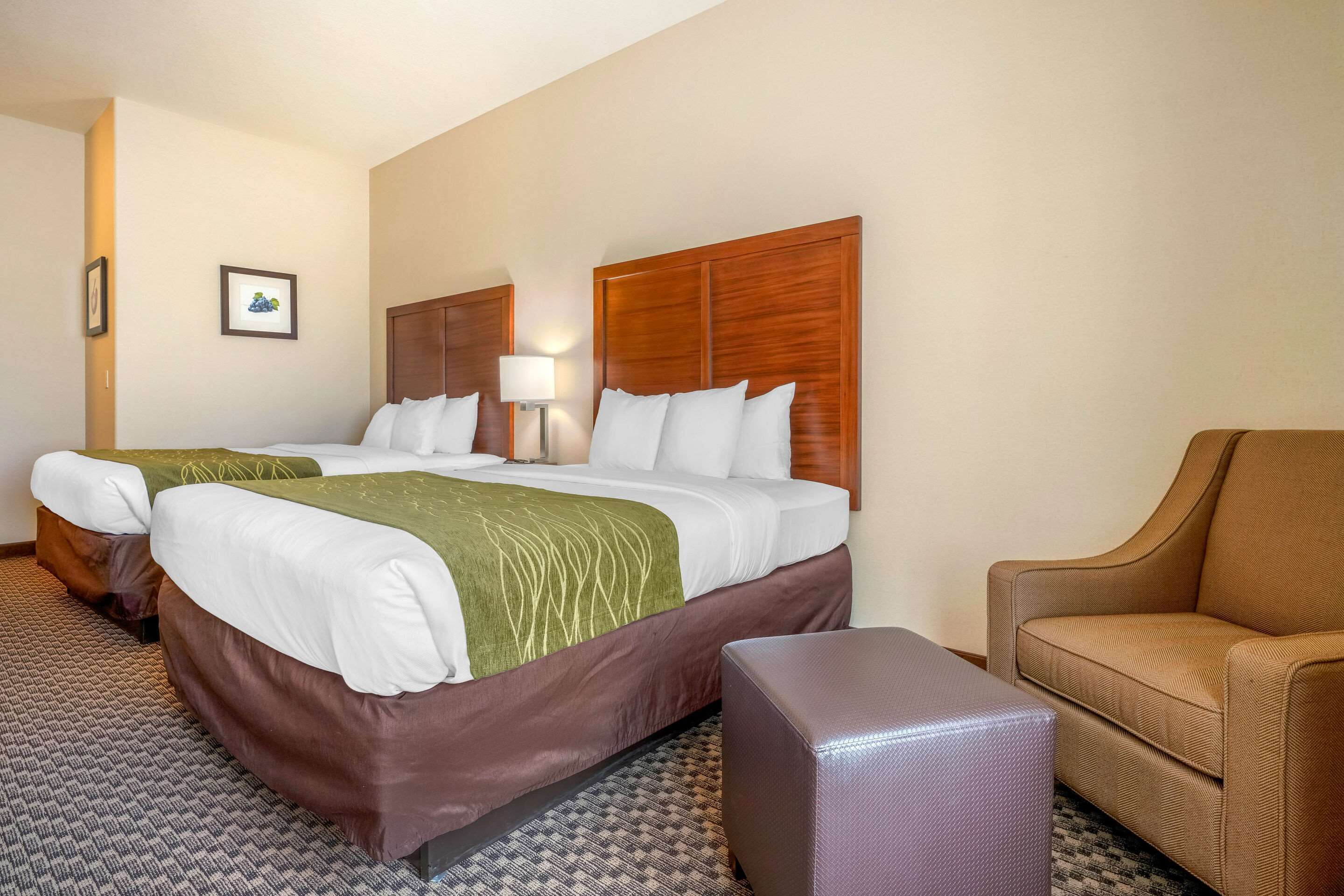 A hotel room with a large bed, a chair, and a small table.