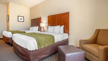 A hotel room with a large bed, a chair, and a small table.