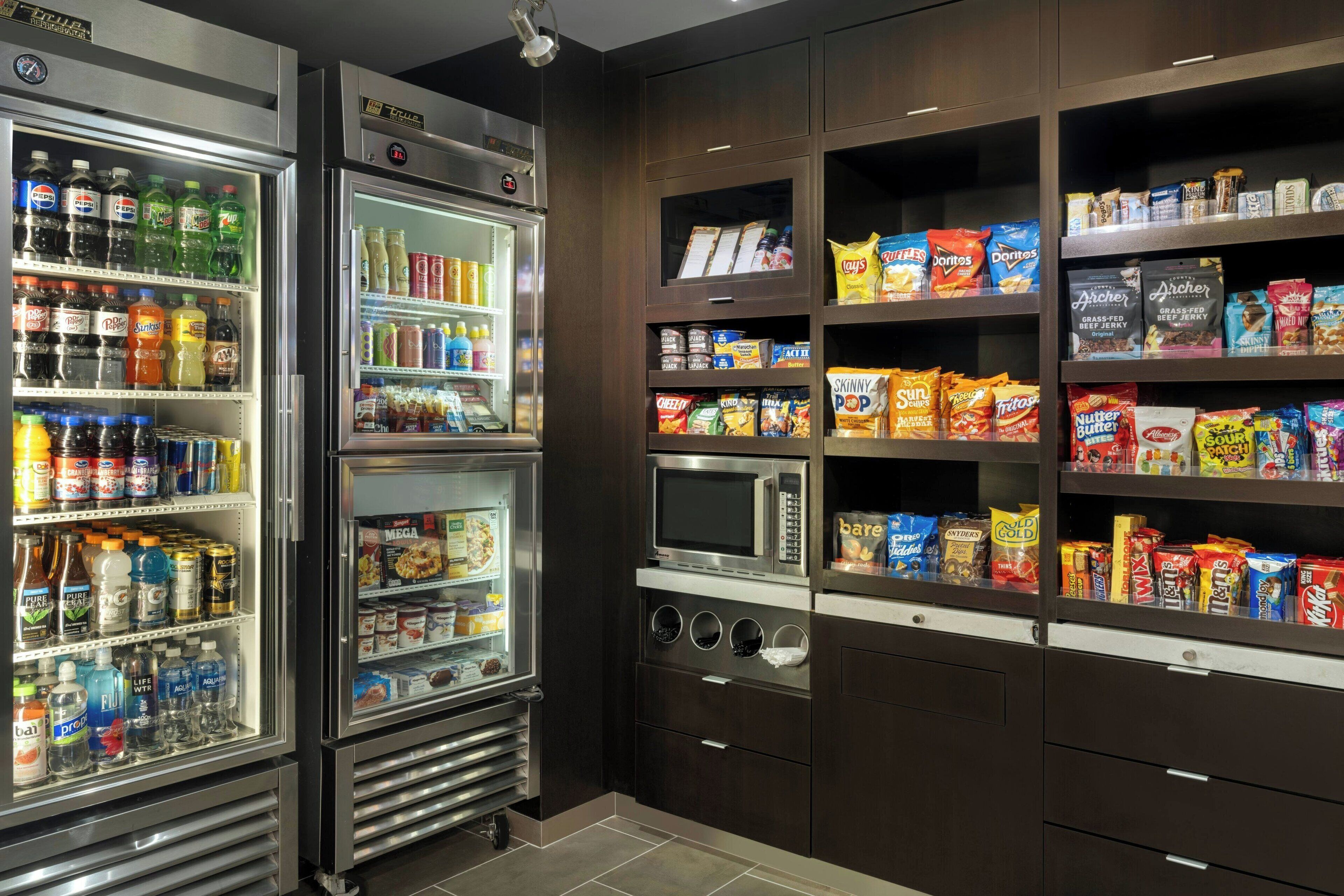 Een openbaar buffet met gekoelde dranken, magnetrons en schappen vol snacks en sauzen.
