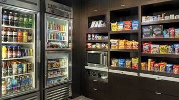 Een openbaar buffet met gekoelde dranken, magnetrons en schappen vol snacks en sauzen.