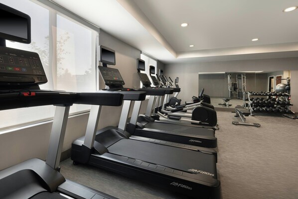 A gym with treadmills, weight machines, and dumbbells.