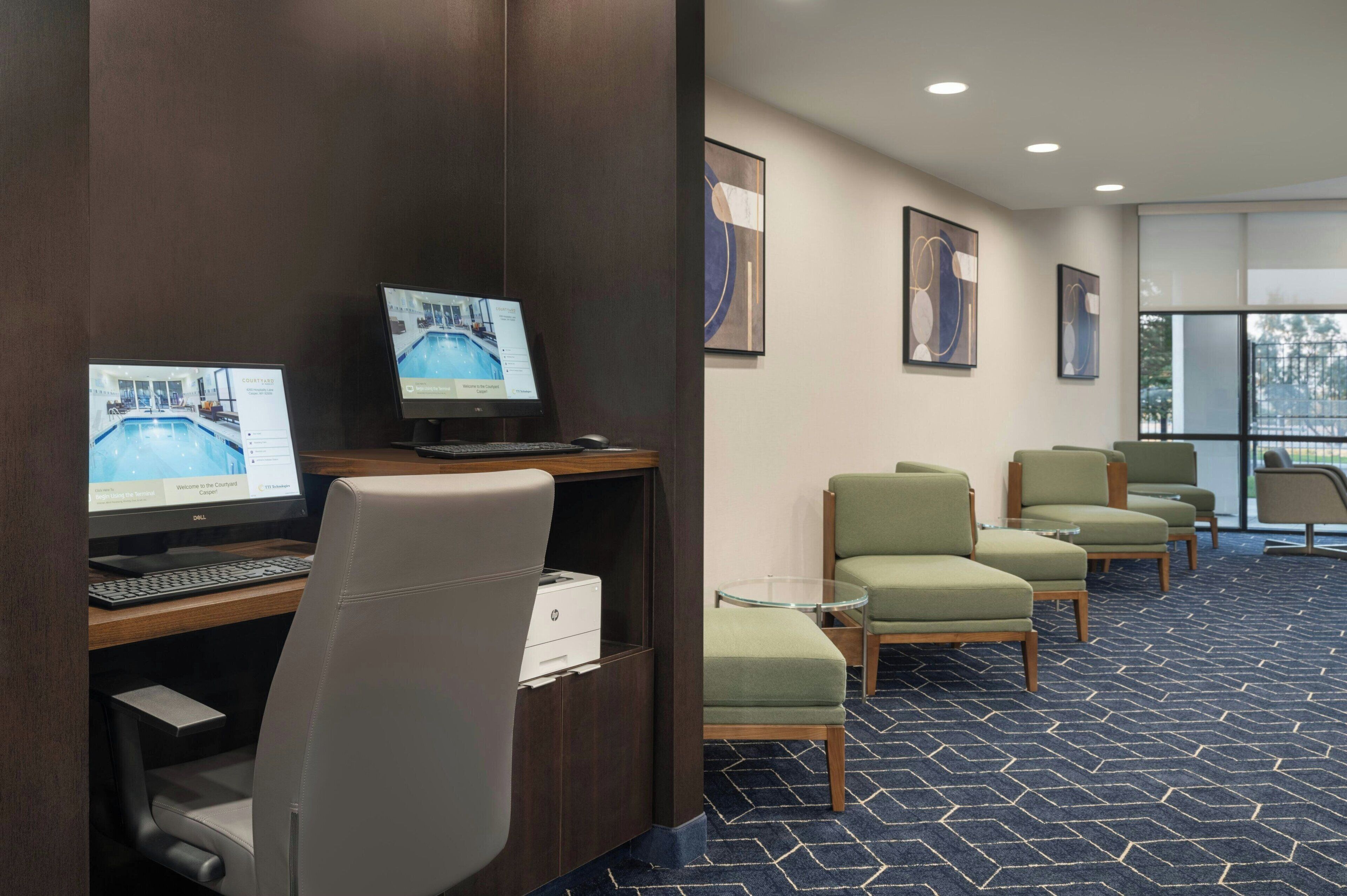 Een hotel lobby met een receptiebalie, computers en een zithoek.