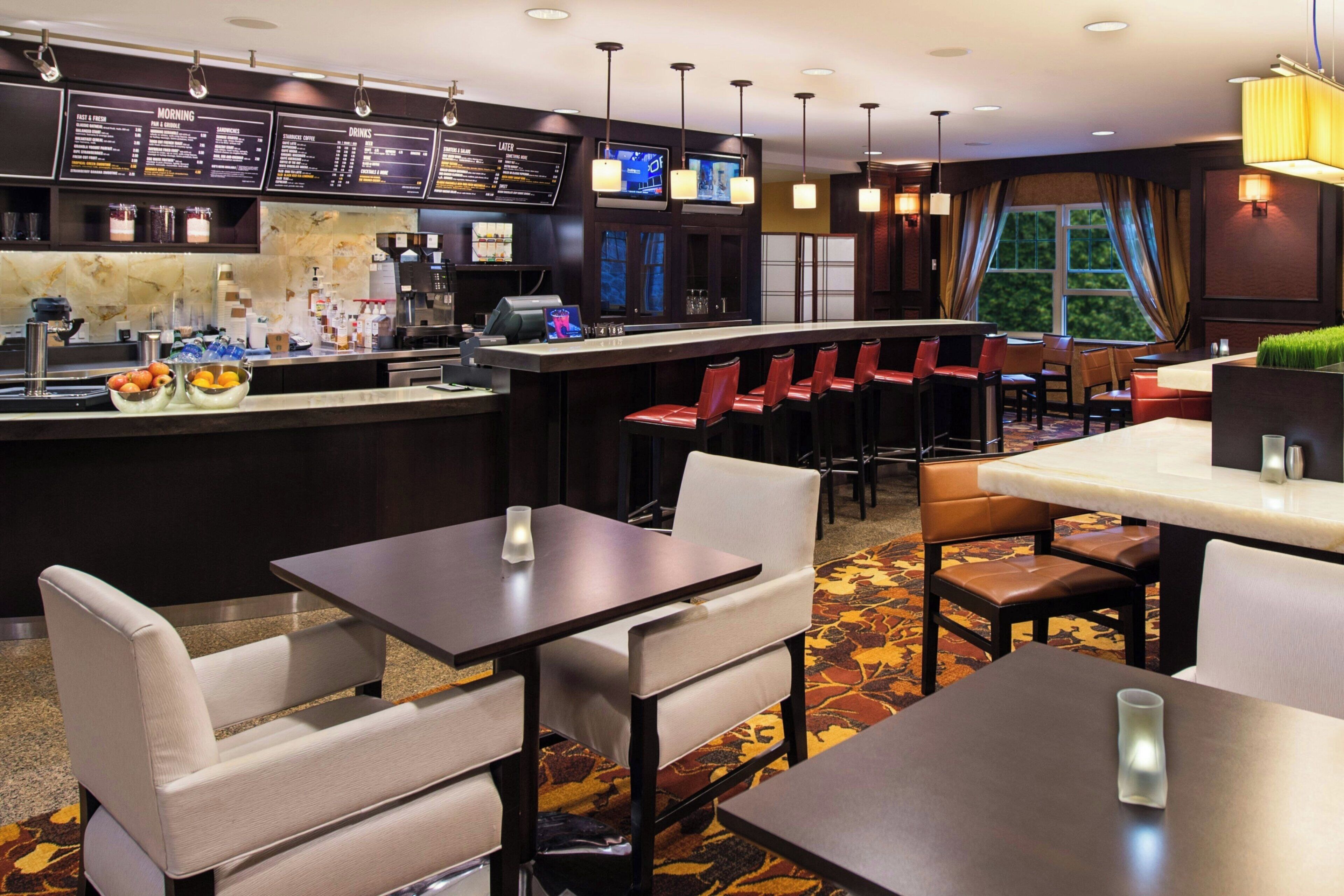 A hotel restaurant with a bar area, seating arrangements, and a menu board.