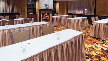 Un salón de conferencias con mesas largas, sillas y una chimenea.