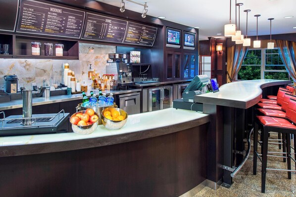 Een moderne bar met een menubord, een toog en zitplaatsen.