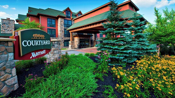 Un hotel Courtyard Marriott con fachada de piedra, techo verde y un cartel.