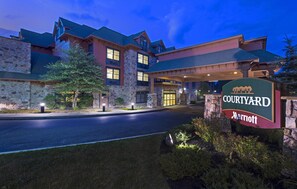 Un hôtel Courtyard Marriott doté d’une façade en pierre, de grandes fenêtres et d’une entrée abritée.