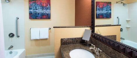 A bathroom with a sink, mirror, towel rack, and shower.