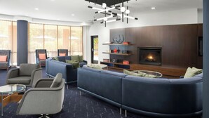 Een moderne woonkamer met een hoekbank, fauteuils en een open haard.