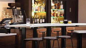 Een bar met een toonbank, krukken en verschillende flessen en glazen.