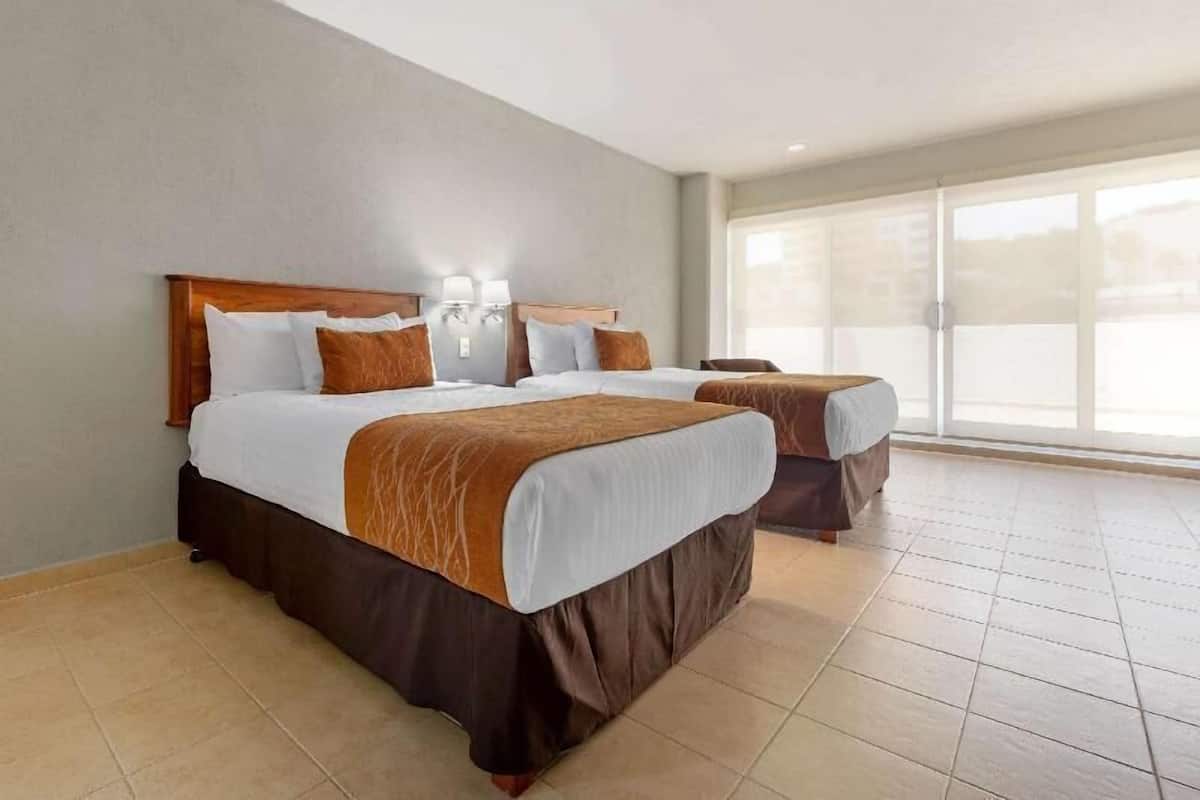 Habitación de hotel con dos camas, un ventanal grande y vistas al exterior.