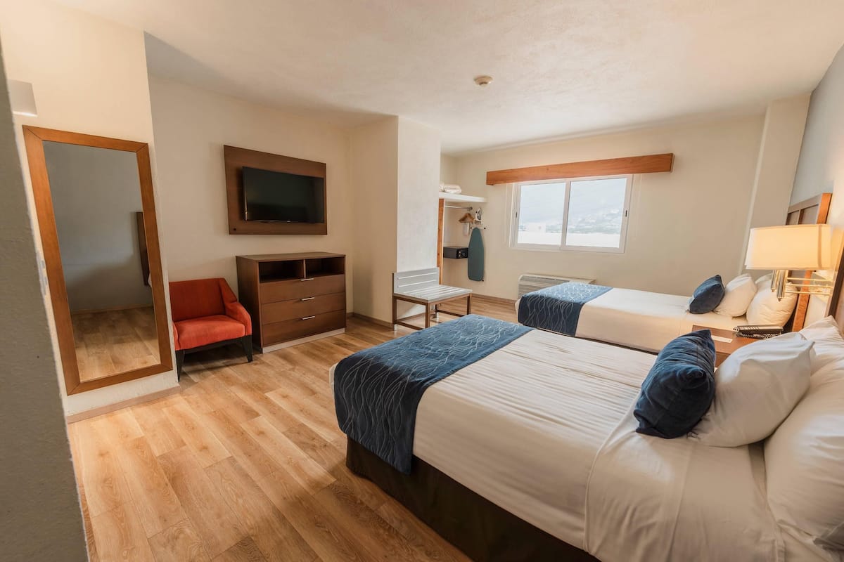 Una habitación de hotel con dos camas, televisión, escritorio y una silla.