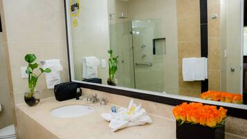 Un baño con un espejo grande, un lavabo y una cabina de ducha de vidrio.