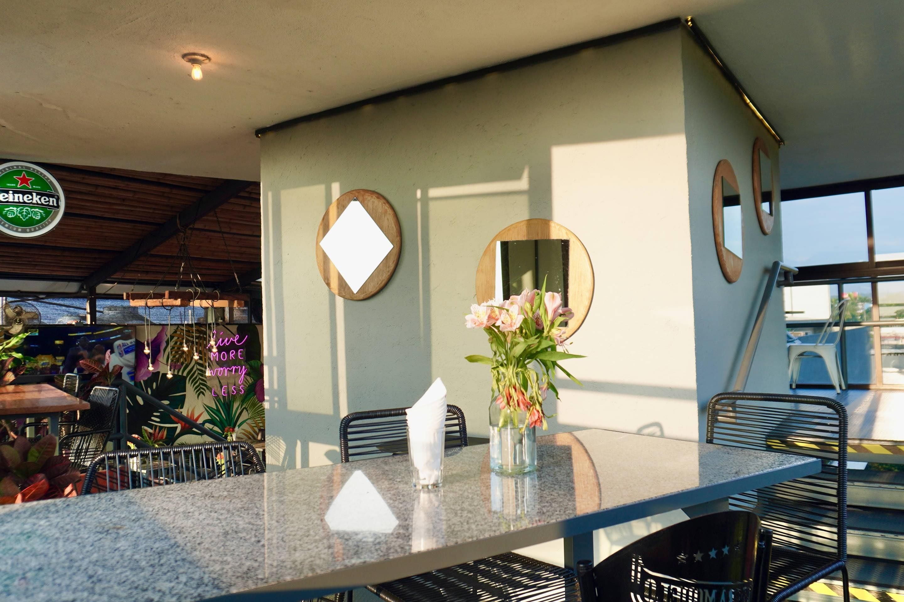 A restaurant interior with a bar area, seating, and decorative elements like a neon sign and wall mirrors.