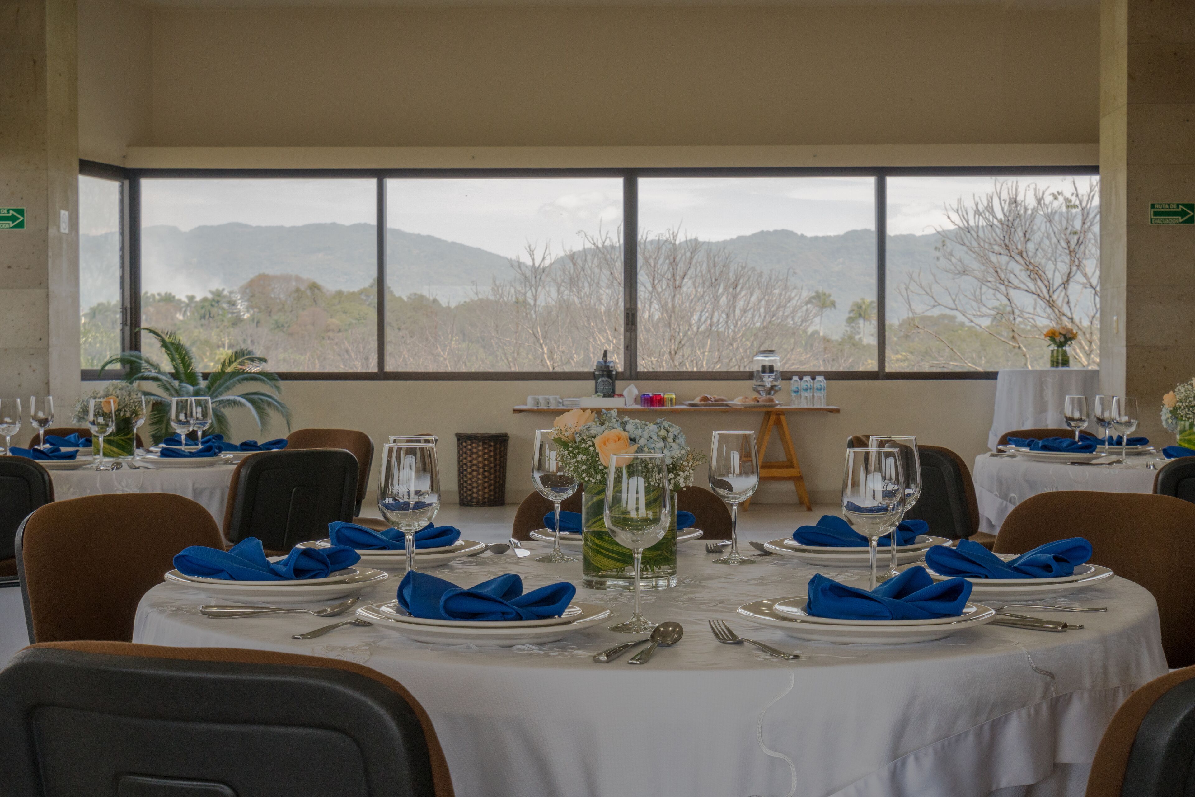 A dining area with tables set for a meal, featuring a mountain view through large windows.
