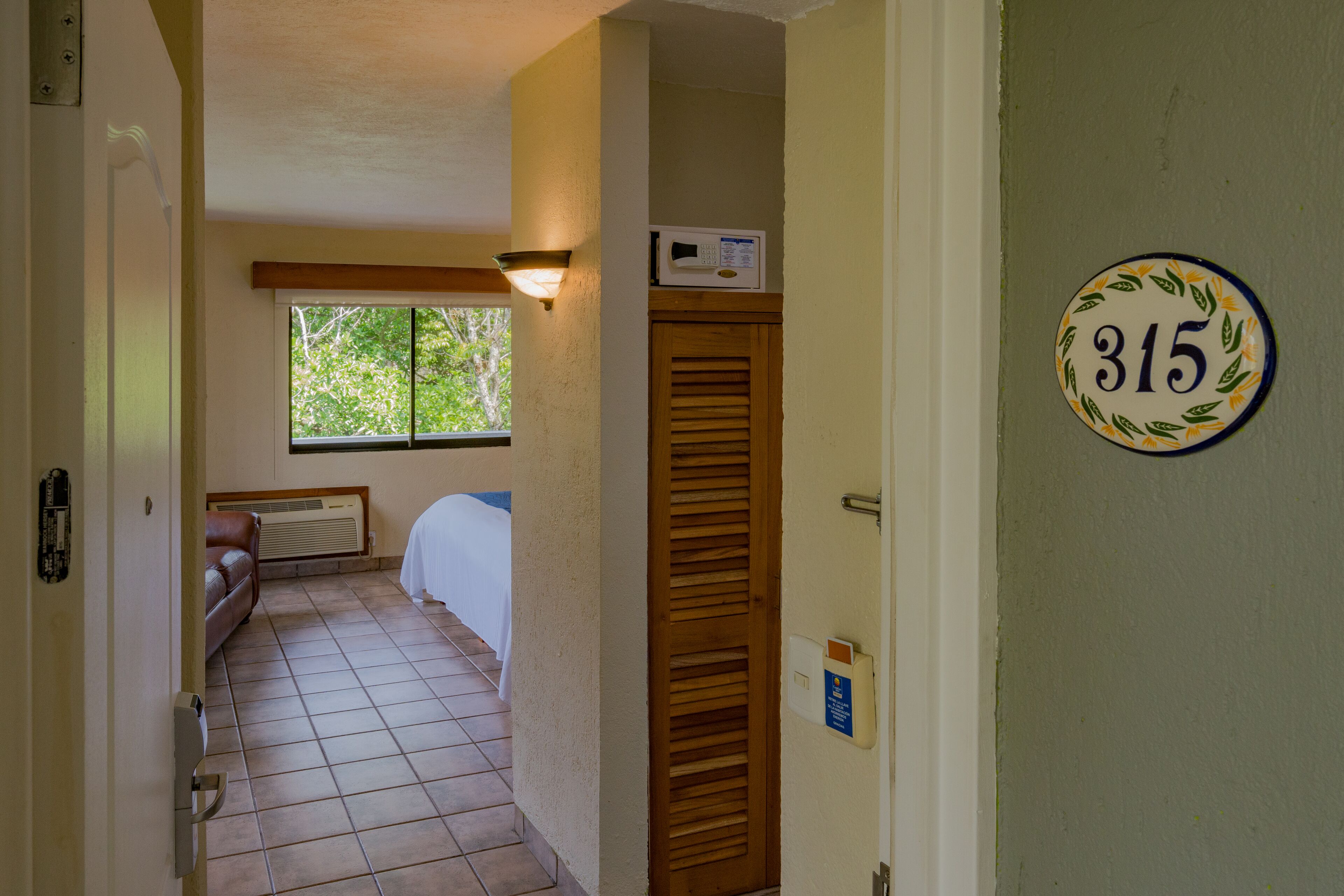 A hallway with a bed, a window, and a door with the number 315.