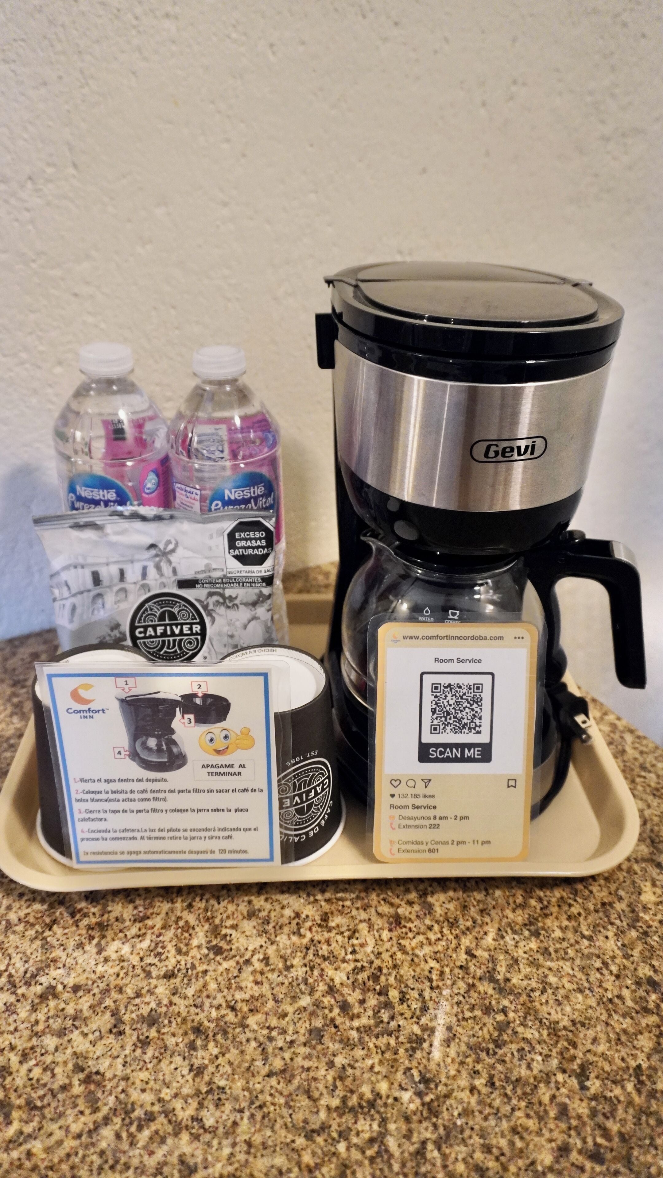 A coffee maker, two water bottles, a coffee pod, and a tray with instructions.