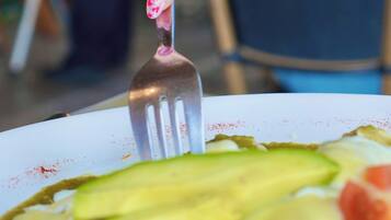 Una mano sosteniendo un tenedor con esmalte rosa brillante, recogiendo comida de un plato.